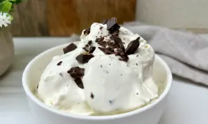 Lody stracciatella w białej miseczce, posypane kawałkami czekolady.