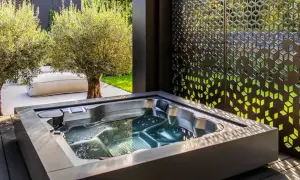 Un jacuzzi moderno en un jardín con olivos y un biombo decorativo. El lugar perfecto para un momento de relax y qué es un chill out.