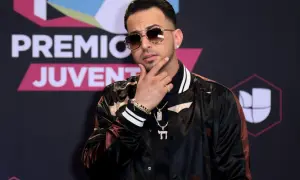 Justin Quiles poses with his hand on his chin, wearing sunglasses and a stylish jacket at Premios Juventud.