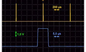 Dwa przebiegi: górny z wąskimi impulsami co 200 µs, dolny z jednym impulsem 5 µs o amplitudzie 1 V. Kwadratowe fale na ekranie oscyloskopu.