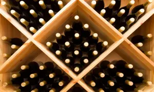 Drewniany stojak na wino wypełniony butelkami.