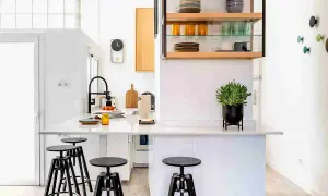 Cocinas sin muebles altos, con una isla central, taburetes negros y estanterías abiertas con vajilla.