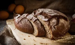 Pane di segale affettato su tagliere, con uova e spighe. Attenzione, il pane di segale fa ingrassare se consumato in eccesso.