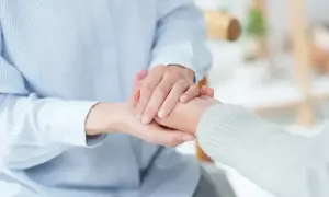 Dwie osoby trzymają się za ręce, symbolizując wsparcie. To obraz, który może kojarzyć się z pomocą finansową, np. świadczenie wspierające kwoty.