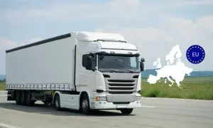 Un camion blanc, d'une hauteur d'un poid lourd, roule sur une route. L'Europe et le drapeau de l'UE sont superposés en arrière-plan.