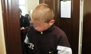 Chłopiec w brązowej bluzie, który jest nieletni, ale w kontekście prawnym może być traktowany jako małoletni.