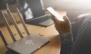 Router i smartfon na biurku. Zastanawiasz się, jak sprawdzić na jakie strony ktoś wchodził wifi?