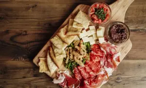 Un beau plateau de charcuterie avec jambon, salami, fromages, pain, olives et tomates.