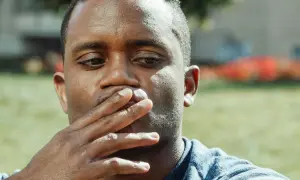 Uomo con mano sulla bocca, pensieroso. Il gesto di coprirsi la bocca può avere un **sputare significato psicologico** di repressione o riflessione interiore.