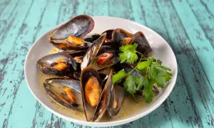 Un plat de moules au roquefort, garni de persil frais, baignant dans une sauce crémeuse. Un délice à savourer.