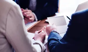 Mötesdeltagare diskuterar dokument och antecknar, kanske för att hantera en force majeure i Sverige.