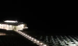 La Rotonda a Mare di Senigallia illuminata di notte, con la passerella che conduce all'edificio e la spiaggia con ombrelloni chiusi.