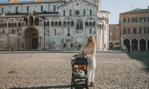 Kobieta z wózkiem dziecięcym na placu przed katedrą w Modenie. To piękne miejsce, które warto zobaczyć, zwłaszcza z taką rodzinną wycieczką.