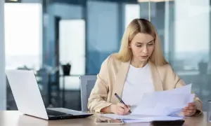 Kobieta w biurze analizuje dokumenty, przygotowując się do udzielenia absolutorium.