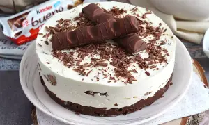 Pyszna tarta Kinder Bueno z kremem i czekoladowymi wiórkami, ozdobiona batonikami.