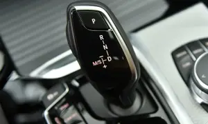 Dźwignia zmiany biegów w BMW G01. Widoczne oznaczenia P, R, N, D oraz M/S z możliwością ręcznej zmiany biegów.