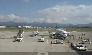 Samolot Ryanair na płycie lotniska Bergamo. W tle góry i budynki lotniskowe.