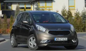 Brązowa Kia Venga z nowymi żarówkami LED, zaparkowana przed nowoczesnym domem.