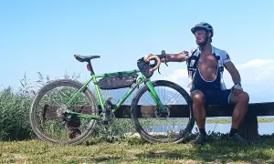 Ciclista riposa accanto alla sua bici verde, un promemoria che andare in bici fa dimagrire e dona benessere.