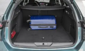 Bagażnik Peugeot 308 SW gotowy na wakacje. W środku niebieska walizka i apteczka.