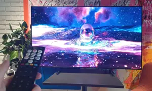 Telewizor wyświetla astronautę w kosmosie, trzymany jest pilot.