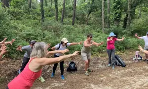 Groupe pratiquant le shinrin yoku en forêt, bras tendus, profitant de la nature.