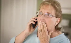 Zaskoczona kobieta rozmawia przez telefon, dowiadując się o zmianach w wypłacaniu emerytury co kwartał.