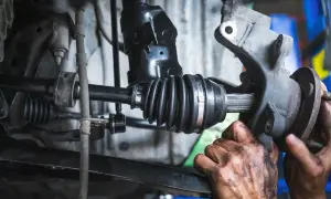Mécanicien travaillant sur un cardan. Le changement cardan prix est une réparation courante.