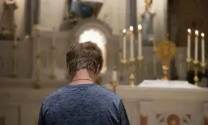 Młody mężczyzna klęczy przed ołtarzem, szukając rozgrzeszenia. Stosunek przerywany może być tematem jego modlitwy.
