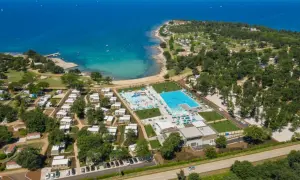 Idealne miejsce, gdzie na wakacje z dziećmi w Europie: kompleks basenów, plaża i domki kempingowe nad turkusowym morzem.