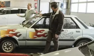 Två män vid en silverfärgad bil med flammor och texten "Ronny & Ragge".
