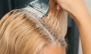 Nakładanie farby na blond włosy, tworząc subtelne refleksy.