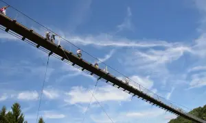 Menschen spazieren auf einer Hängebrücke im Himmel. Ein tolles geheimes Ausflugsziel in Rheinland-Pfalz für Abenteuerlustige.