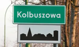 Znak drogowy z napisem Kolbuszowa i sylwetką miasta. To znak d42, informujący o wjeździe do miejscowości.