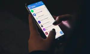 Dłonie trzymają smartfon z otwartą aplikacją Telegram. Czy telegram jest bezpieczny? To pytanie nurtuje wielu użytkowników komunikatorów.