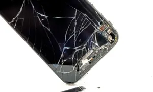 Rozbite szkło telefonu. Widać pęknięcia i fragmenty, które odpadły. To pokazuje, czym się różni szkło hartowane od hybrydowego w praktyce.