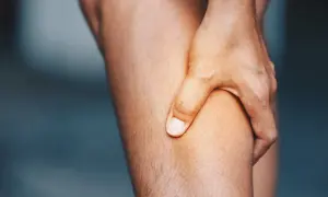 Hand greift an schmerzendes Bein. Was hilft gegen Muskelschmerzen?