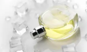Szklana buteleczka perfum z żółtym płynem, otoczona kostkami lodu. Wyobraź sobie orzeźwiający, szyprowy zapach.