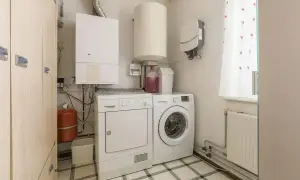 Pomieszczenie gospodarcze w domu z pralką, suszarką, bojlerem i kotłem.