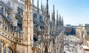 Majestatyczne iglice katedry Duomo w Mediolanie w marcu, z tłumem ludzi spacerującym po placu poniżej.