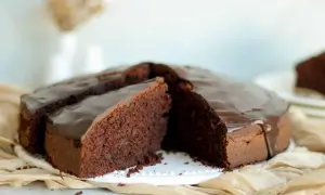 Saftiger Schokokuchen mit glänzender Glasur, perfekt für ein schnelles schokokuchen rezept. Ein Stück ist bereits angeschnitten.