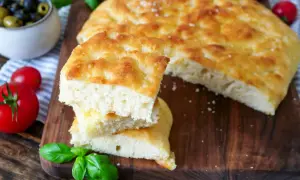 Fluffiges Focaccia-Rezept: goldbraunes Brot mit knuspriger Kruste und weicher Krume, garniert mit frischem Basilikum und Tomaten.