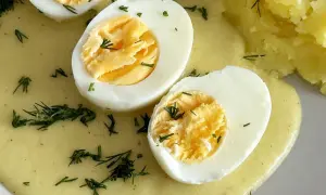 Jajka w sosie musztardowym, udekorowane koperkiem, obok purée ziemniaczane. Pyszne danie na obiad.