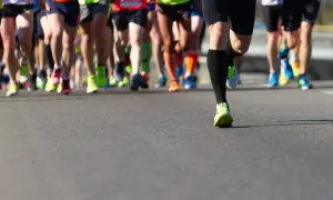 Gambe di corridori in maratona, con scarpe colorate. Un esempio di tabella maratona 4 allenamenti settimanali.