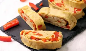 Roladki omlet tamago z papryką, ułożone na czarnej desce.