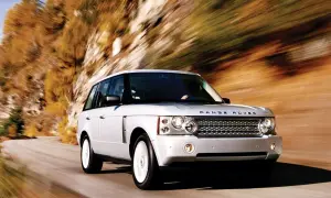 Biały Range Rover L322 pędzi po krętej drodze wśród jesiennych drzew.