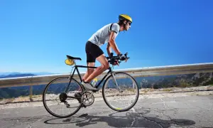 Kolarz w kasku i okularach pokonuje górską trasę. Czy 100 km na rowerze to dużo? Dla niego to wyzwanie!