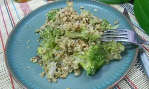 Un délicieux crumble brocolis aux noix, servi sur une assiette bleue.
