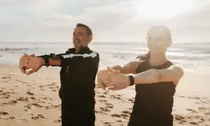 Para ćwiczy na plaży, ciesząc się słońcem i morzem. Idealne miejsce na turnusy rehabilitacyjne nad morzem.
