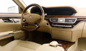 Wnętrze luksusowego Mercedesa S 500 z beżową skórzaną tapicerką, drewnianymi wstawkami i kierownicą.